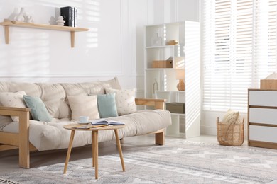 Photo of Beautiful sofa with cushions and coffee table in living room. Interior design