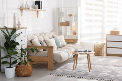 Photo of Beautiful sofa with cushions and coffee table in living room. Interior design