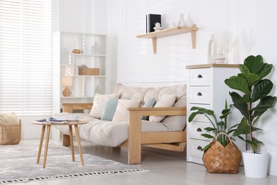 Photo of Beautiful sofa with cushions and coffee table in living room. Interior design