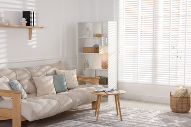 Photo of Beautiful sofa with cushions and coffee table in living room. Interior design