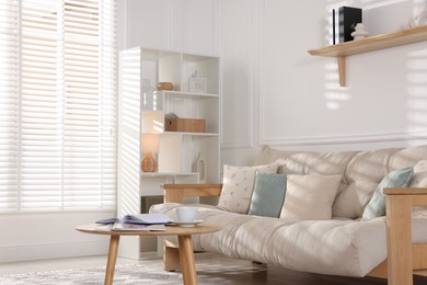 Photo of Beautiful sofa with cushions and coffee table in living room. Interior design