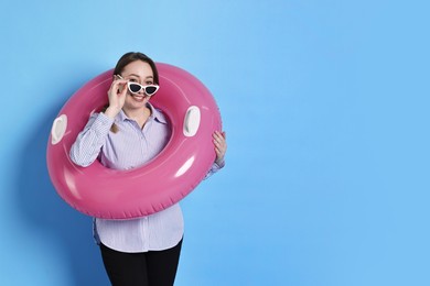 Photo of Businesswoman with inflatable ring and sunglasses on light blue background, space for text