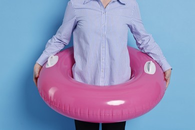 Photo of Businesswoman with inflatable ring on light blue background, closeup