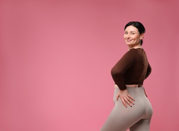 Photo of Plus size woman in gym clothes on pink background, space for text