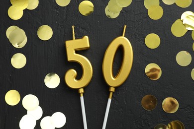 Photo of 50th birthday. Number shaped candles and confetti on black background, flat lay