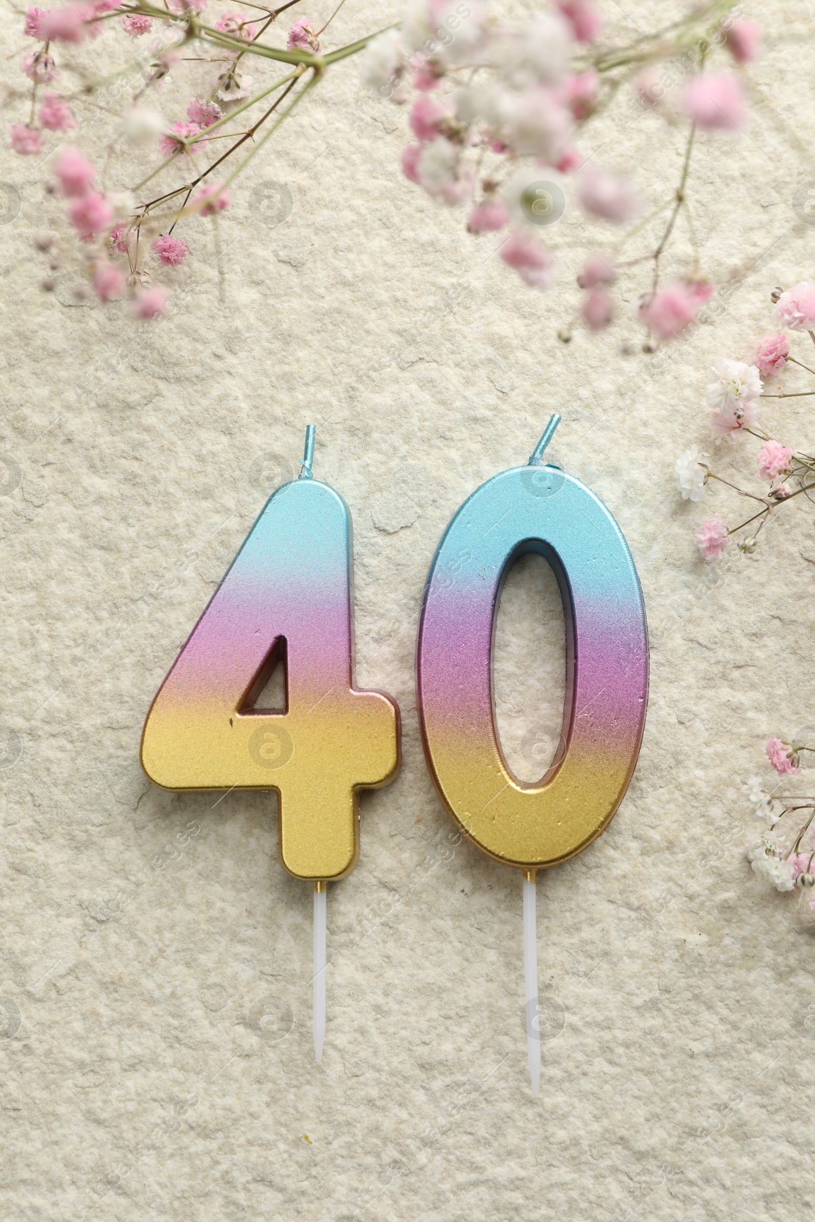 Photo of 40th birthday. Number shaped candles and flowers on light textured background, flat lay