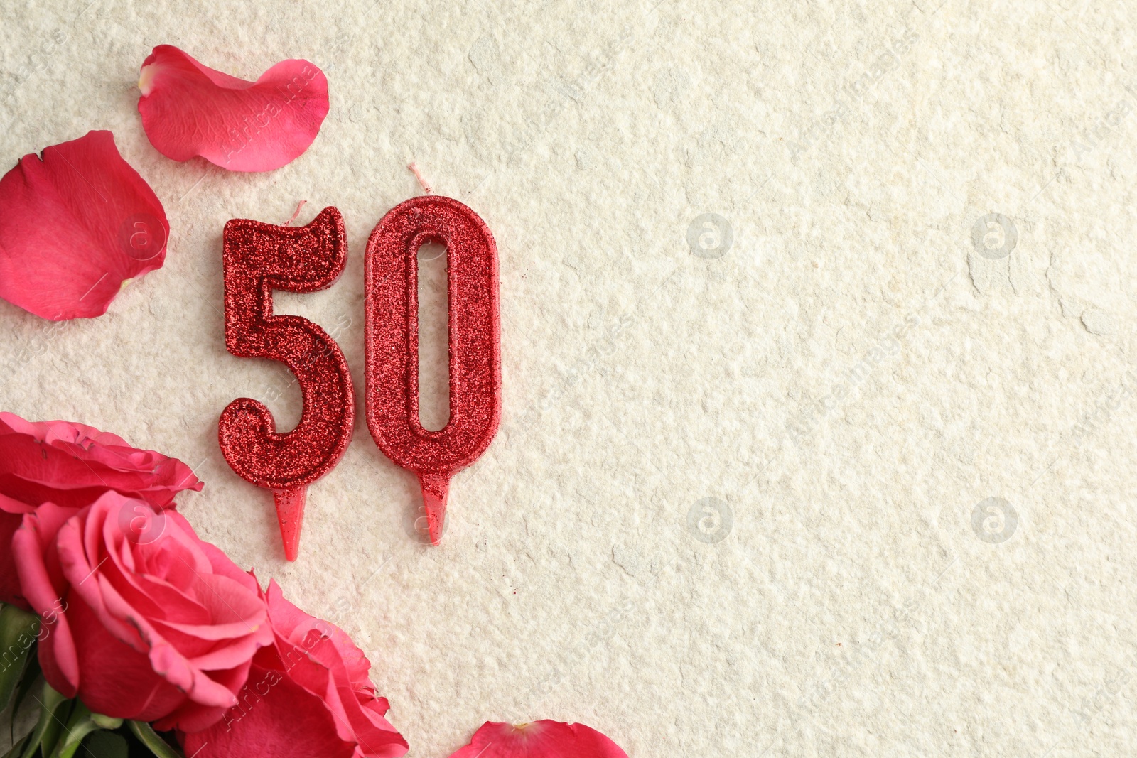 Photo of 50th birthday. Number shaped candles and roses on light textured background, flat lay. Space for text