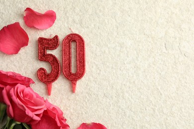 Photo of 50th birthday. Number shaped candles and roses on light textured background, flat lay. Space for text