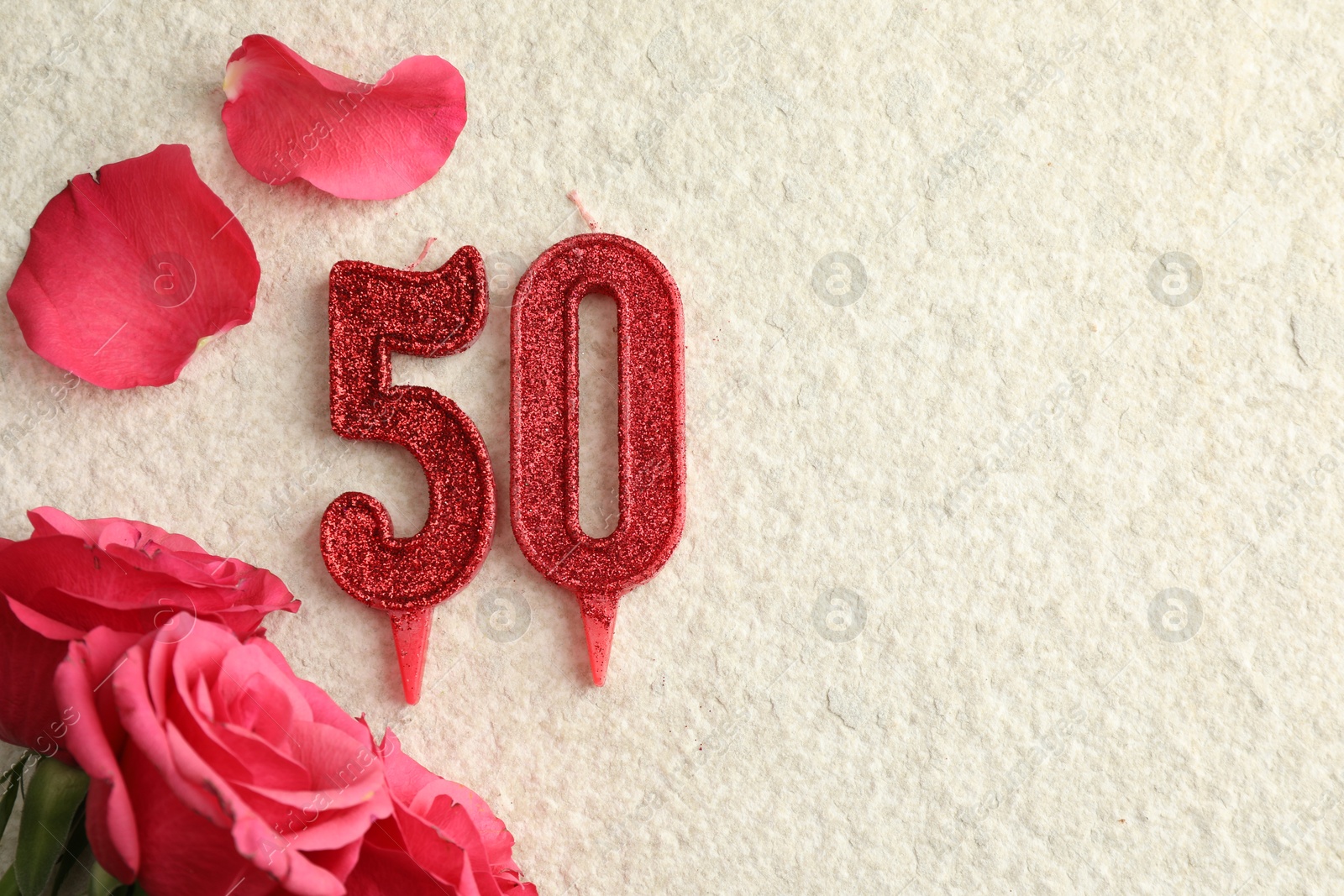 Photo of 50th birthday. Number shaped candles and roses on light textured background, flat lay. Space for text