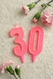 Photo of 30th birthday. Number shaped candles and flowers on light textured background, flat lay