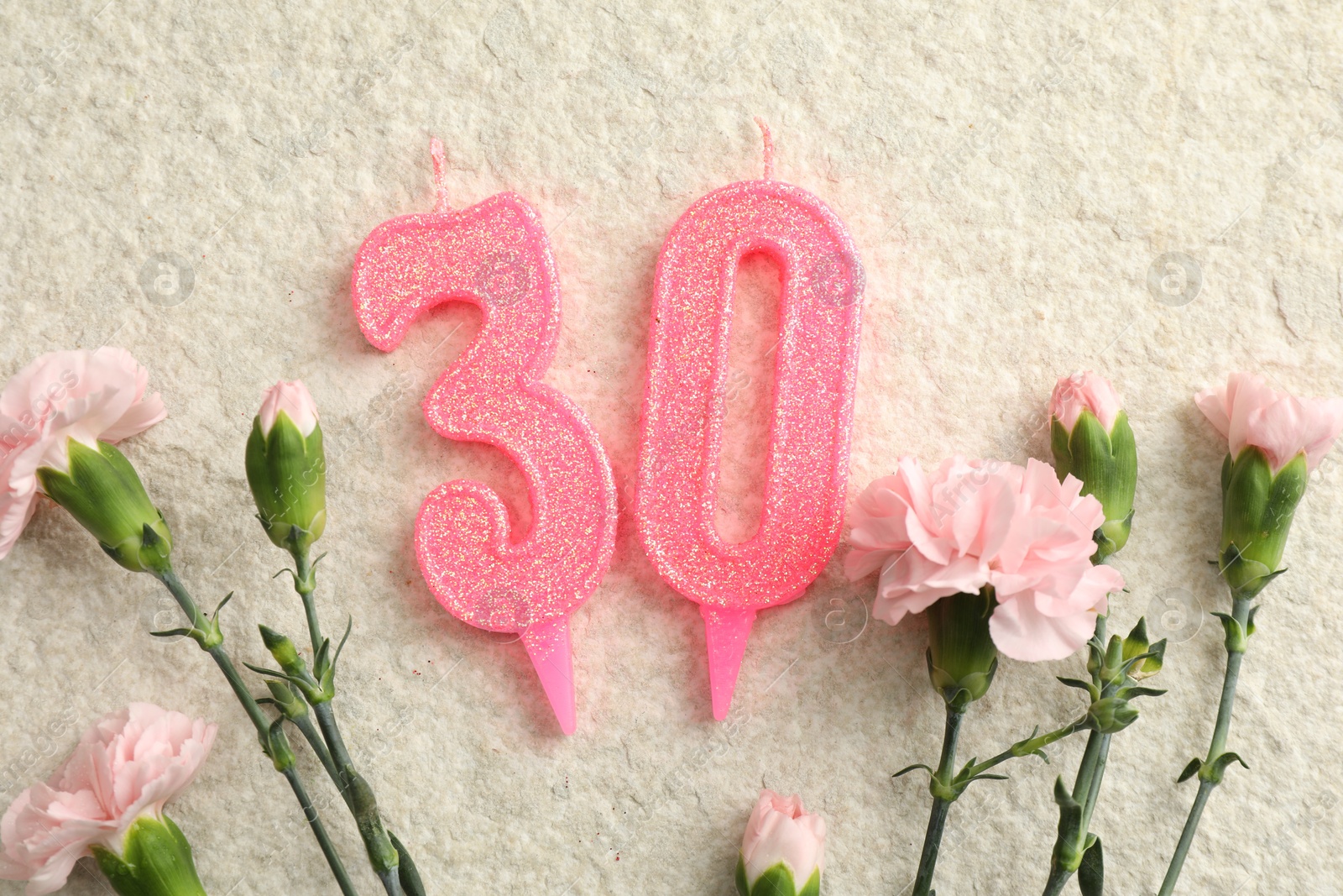 Photo of 30th birthday. Number shaped candles and flowers on light textured background, flat lay