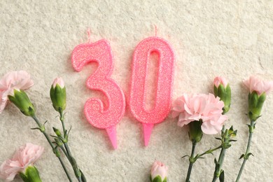 Photo of 30th birthday. Number shaped candles and flowers on light textured background, flat lay