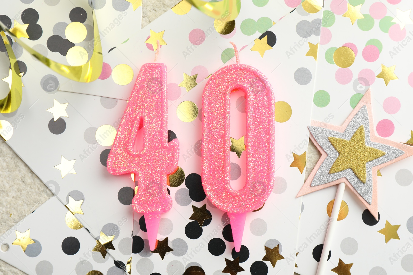 Photo of 40th birthday. Number shaped candles, party decor and confetti on light textured background, flat lay