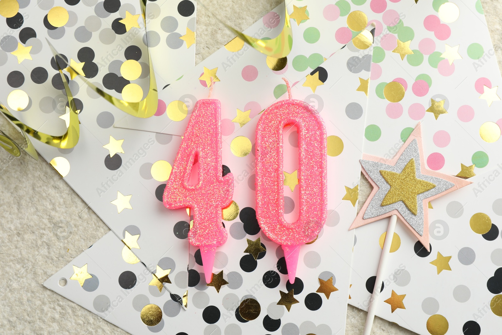 Photo of 40th birthday. Number shaped candles, party decor and confetti on light textured background, flat lay