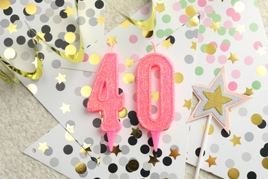 Photo of 40th birthday. Number shaped candles, party decor and confetti on light textured background, flat lay