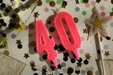 Photo of 40th birthday. Number shaped candles, party decor and confetti on light textured background, flat lay