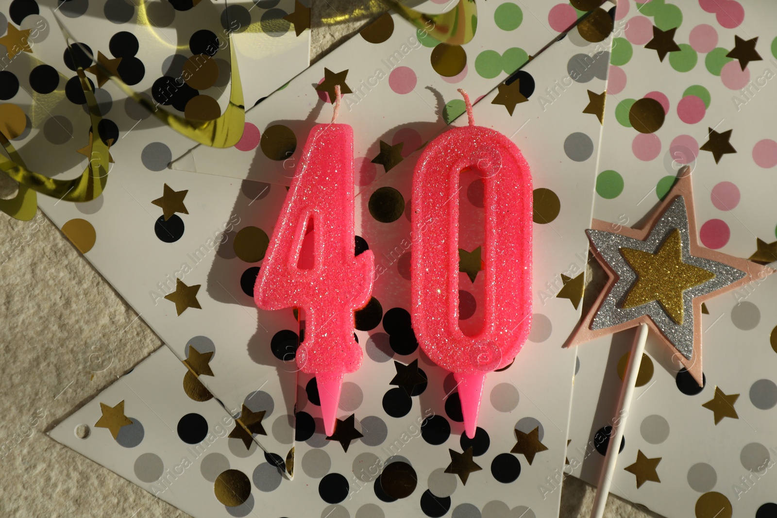 Photo of 40th birthday. Number shaped candles, party decor and confetti on light textured background, flat lay