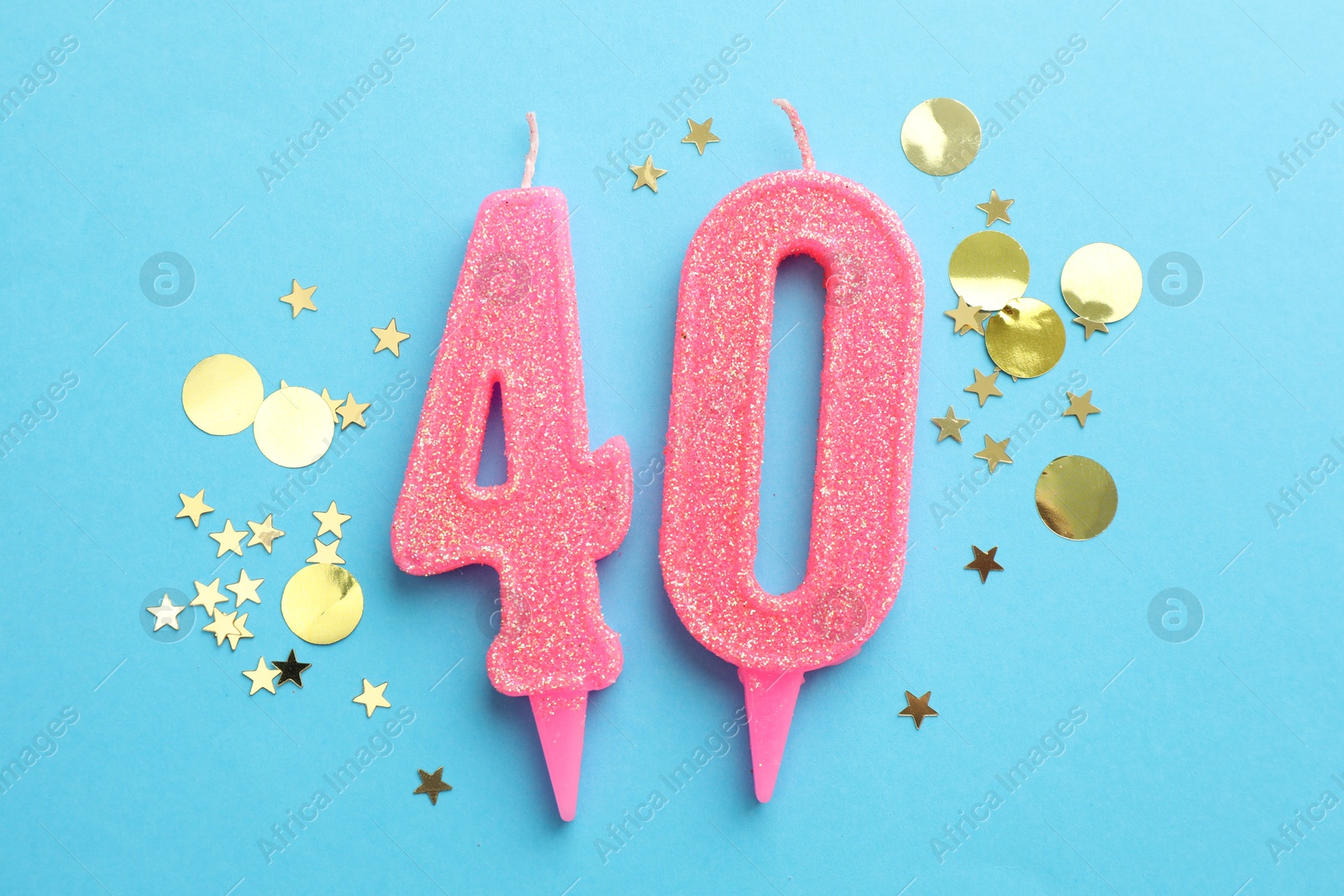 Photo of 40th birthday. Number shaped candles and confetti on light blue background, flat lay