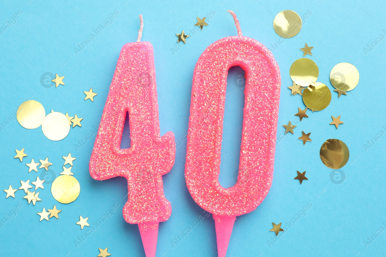 Photo of 40th birthday. Number shaped candles and confetti on light blue background, flat lay