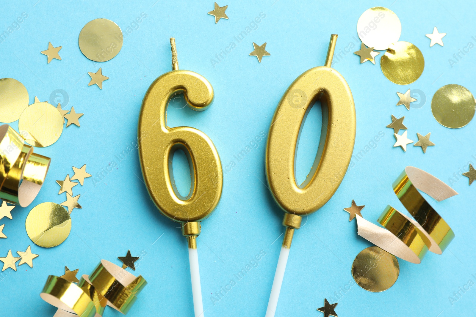 Photo of 60th birthday. Number shaped candles and confetti on light blue background, flat lay