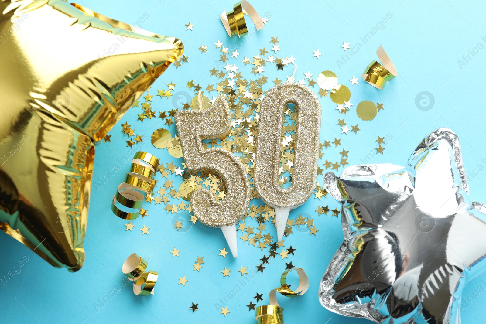 Photo of 50th birthday. Number shaped candles, balloons and confetti on light blue background, flat lay