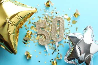 Photo of 50th birthday. Number shaped candles, balloons and confetti on light blue background, flat lay