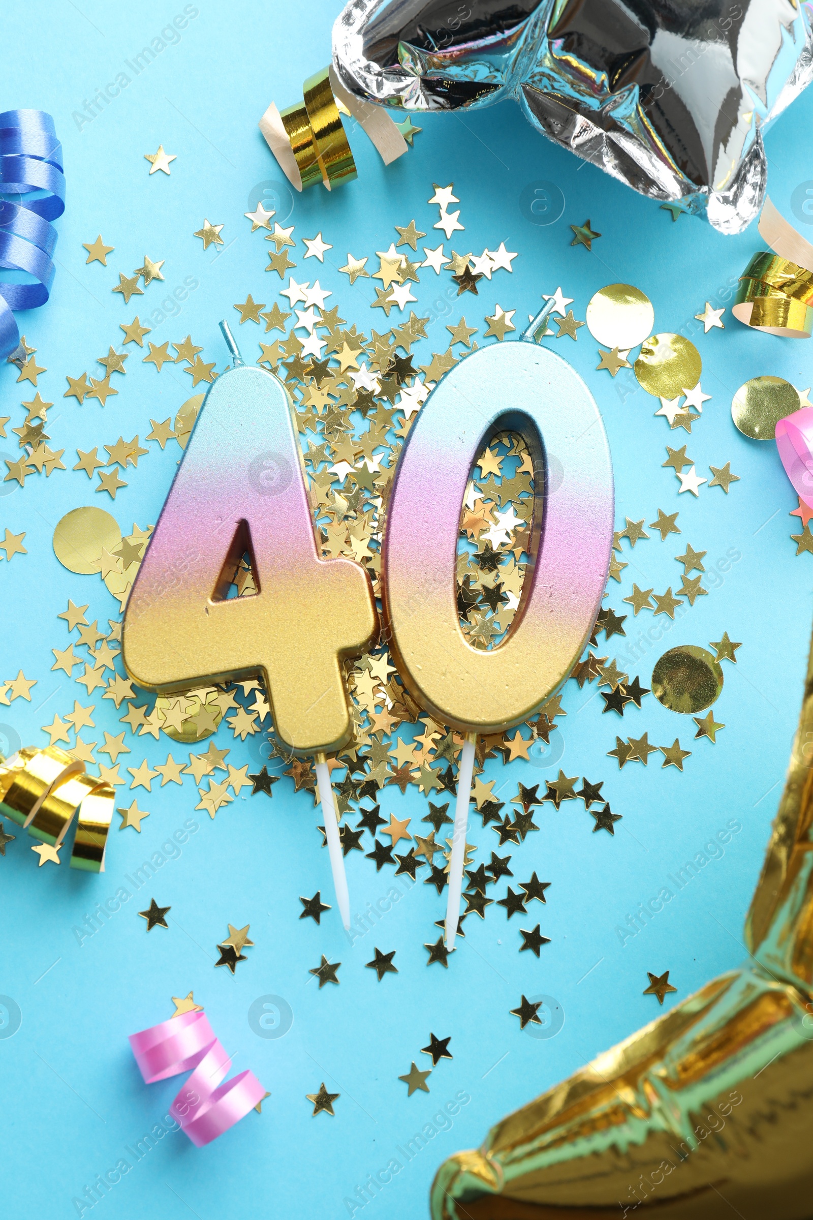 Photo of 40th birthday. Number shaped candles and party decor on light blue background, flat lay