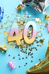 Photo of 40th birthday. Number shaped candles and party decor on light blue background, flat lay