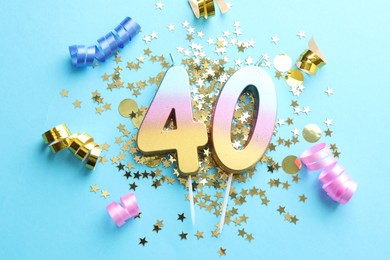 Photo of 40th birthday. Number shaped candles and party decor on light blue background, flat lay