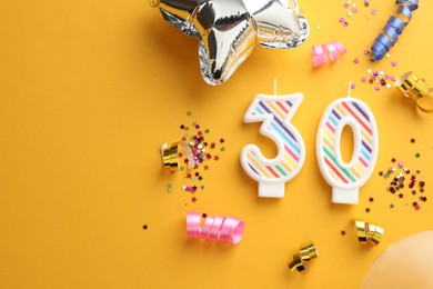 Photo of 30th birthday. Number shaped candles and party decor on orange background, flat lay. Space for text