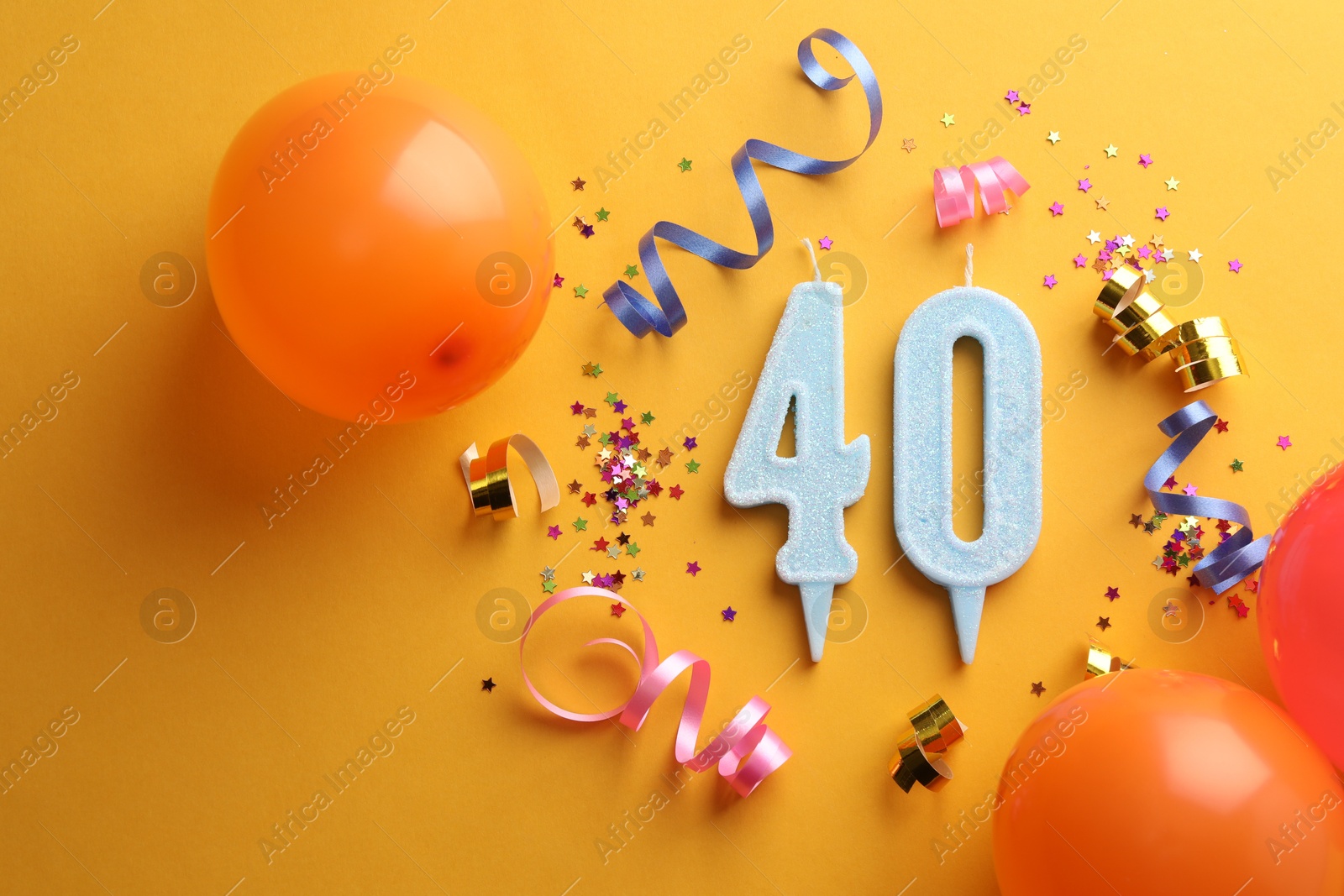 Photo of 40th birthday. Number shaped candles and party decor on orange background, flat lay