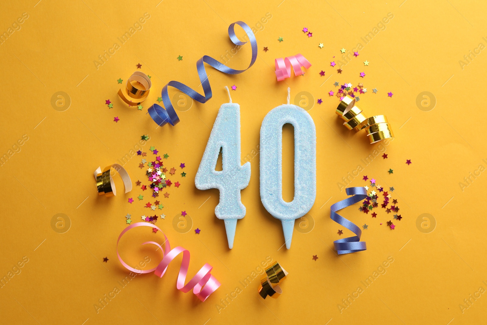 Photo of 40th birthday. Number shaped candles and party decor on orange background, flat lay