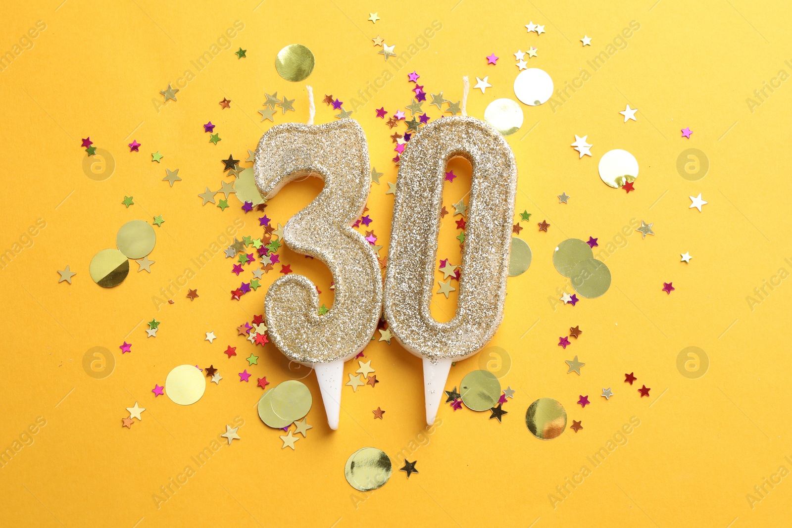 Photo of 30th birthday. Number shaped candles and confetti on orange background, flat lay