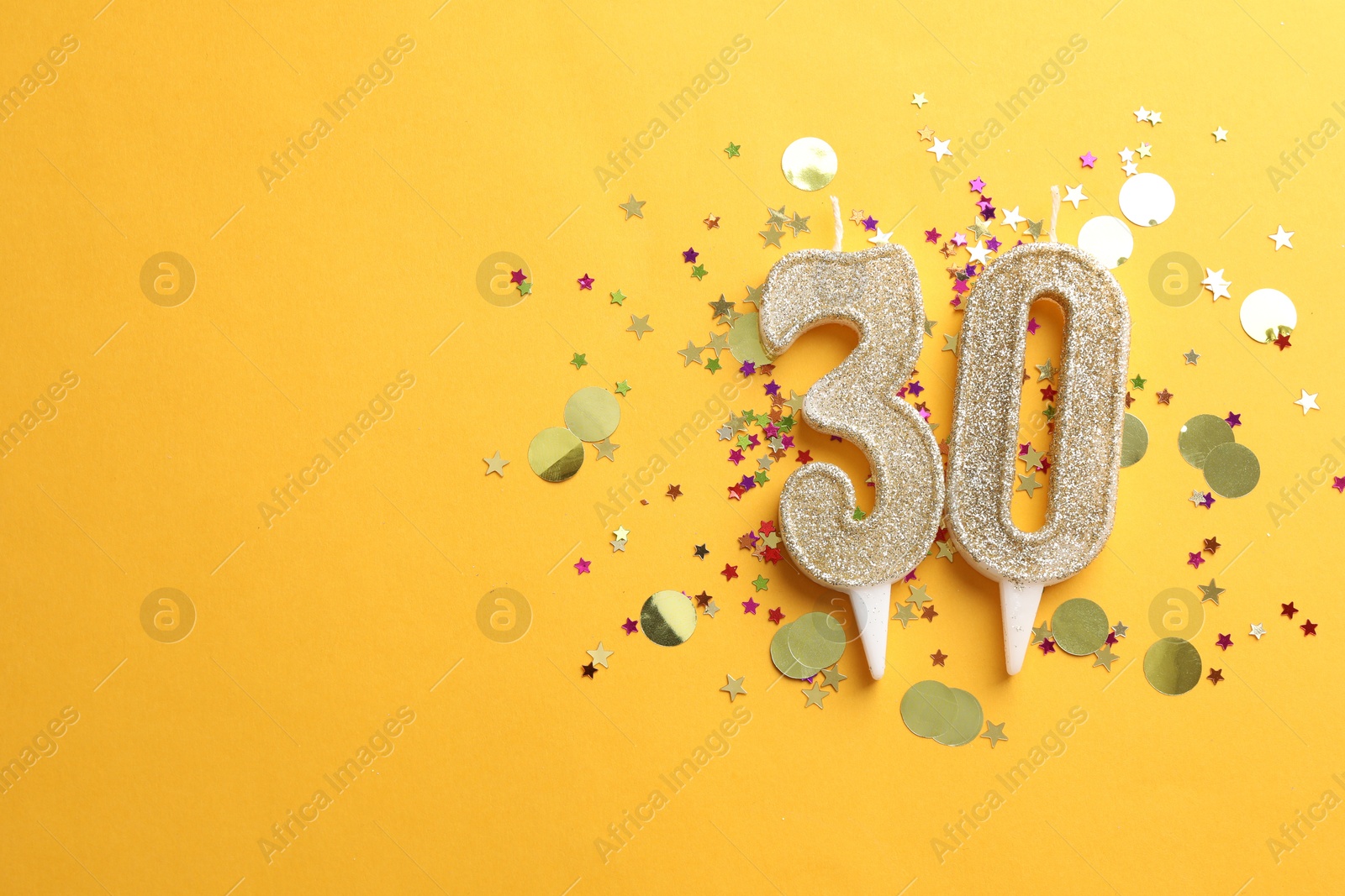 Photo of 30th birthday. Number shaped candles and confetti on orange background, flat lay. Space for text