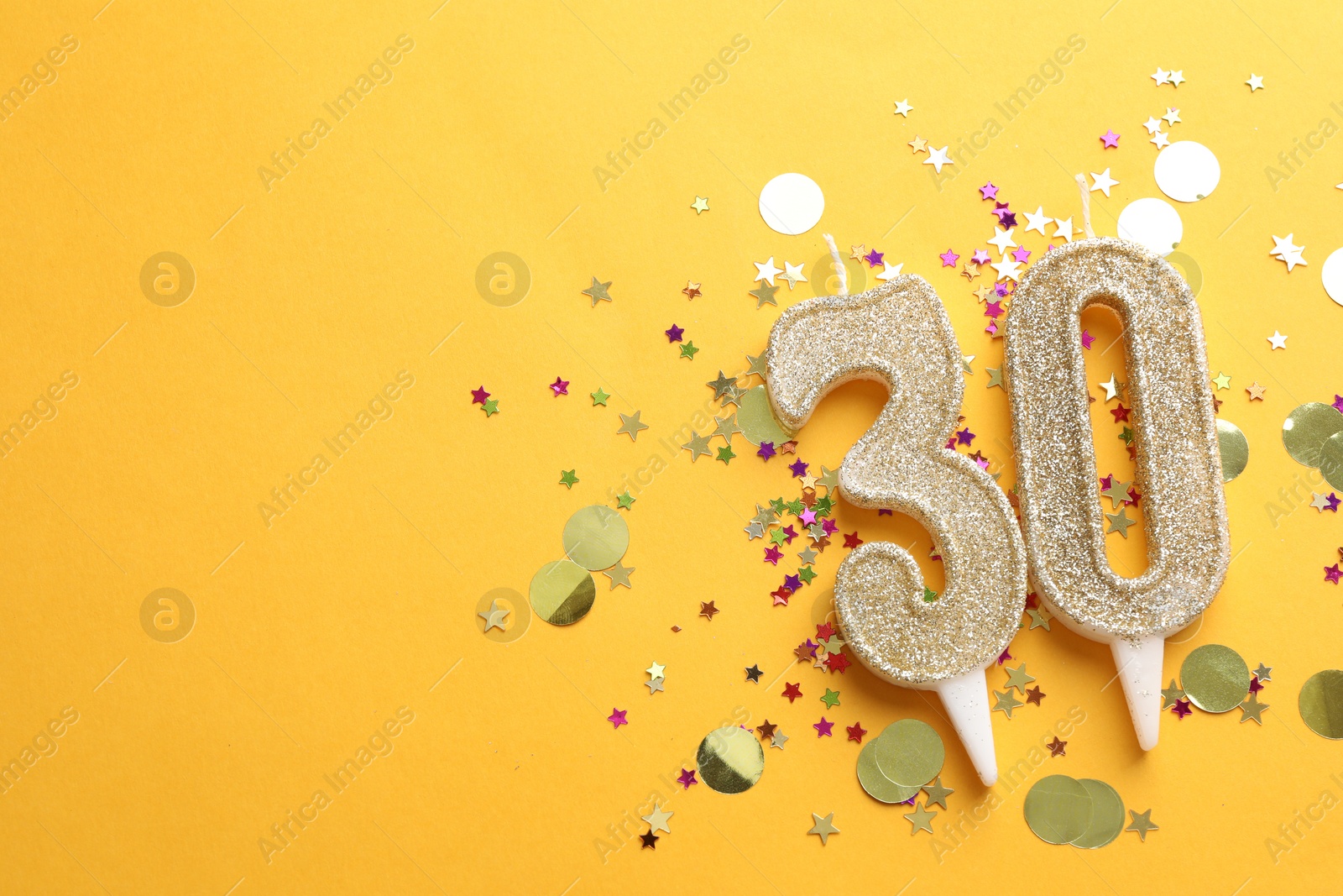 Photo of 30th birthday. Number shaped candles and confetti on orange background, flat lay. Space for text