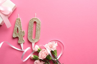 Photo of 40th birthday. Number shaped candles, gift and flowers on pink background, flat lay. Space for text