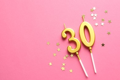 Photo of 30th birthday. Number shaped candles and confetti on pink background, flat lay. Space for text