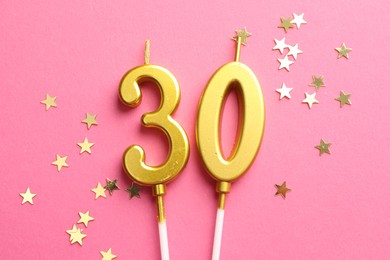 Photo of 30th birthday. Number shaped candles and confetti on pink background, flat lay