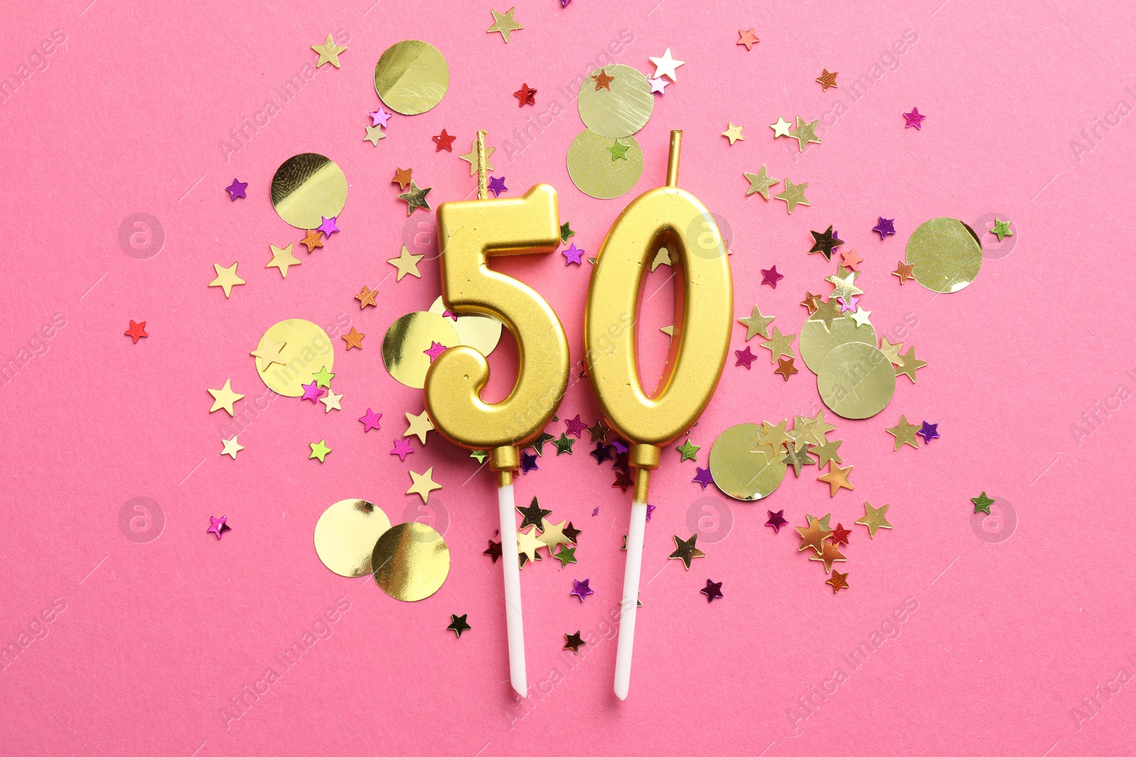 Photo of 50th birthday. Number shaped candles and confetti on pink background, flat lay