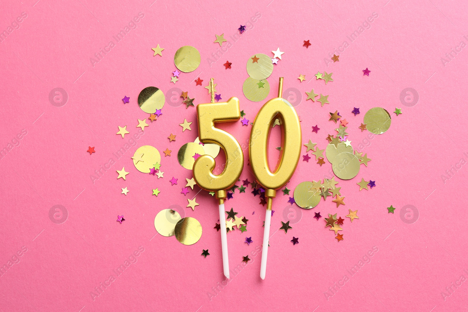 Photo of 50th birthday. Number shaped candles and confetti on pink background, flat lay