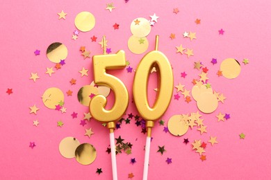 Photo of 50th birthday. Number shaped candles and confetti on pink background, flat lay