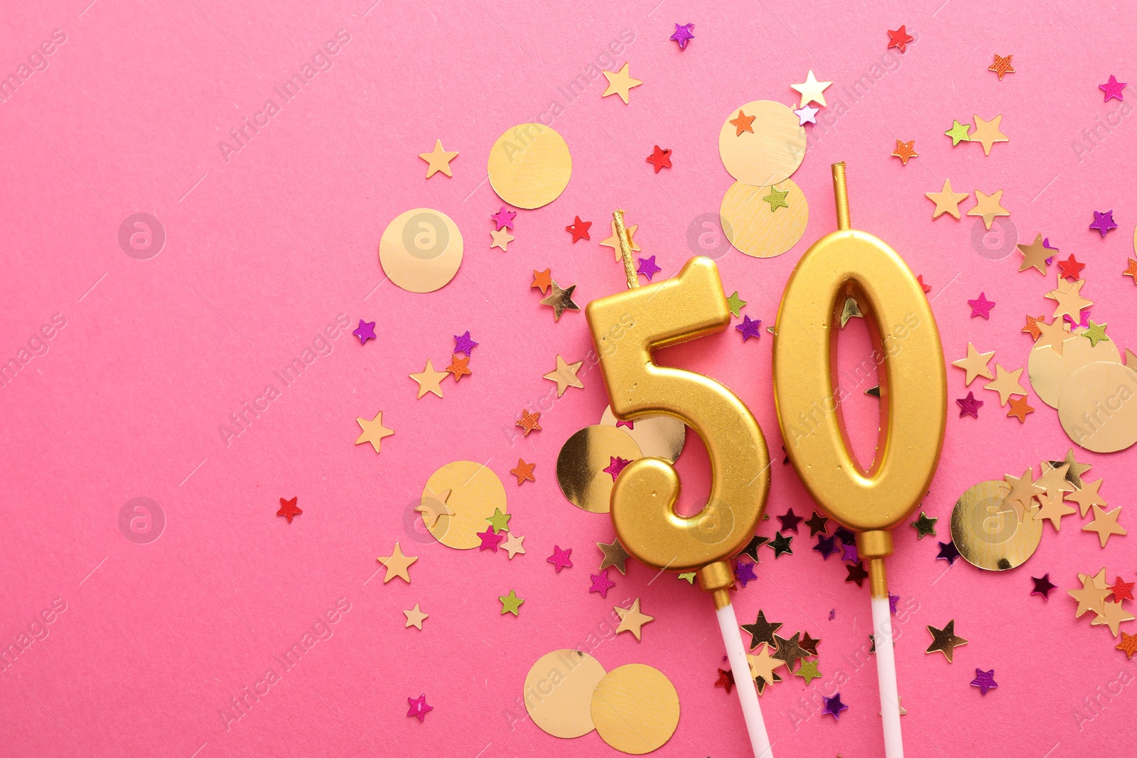 Photo of 50th birthday. Number shaped candles and confetti on pink background, flat lay. Space for text