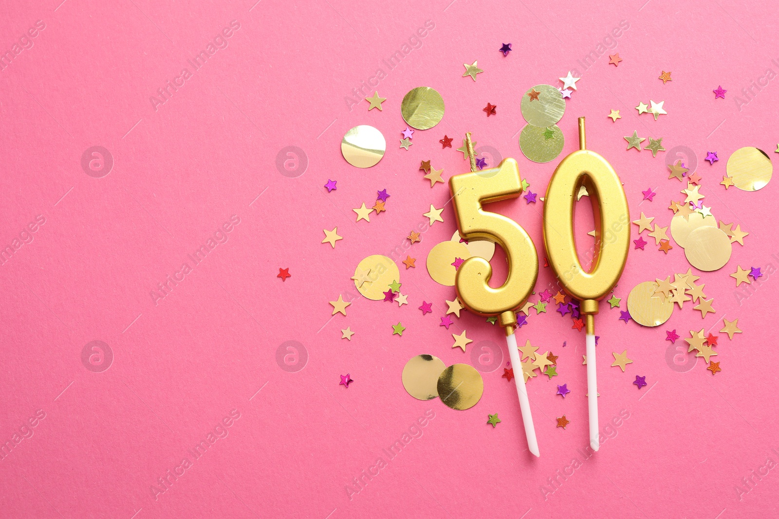 Photo of 50th birthday. Number shaped candles and confetti on pink background, flat lay. Space for text