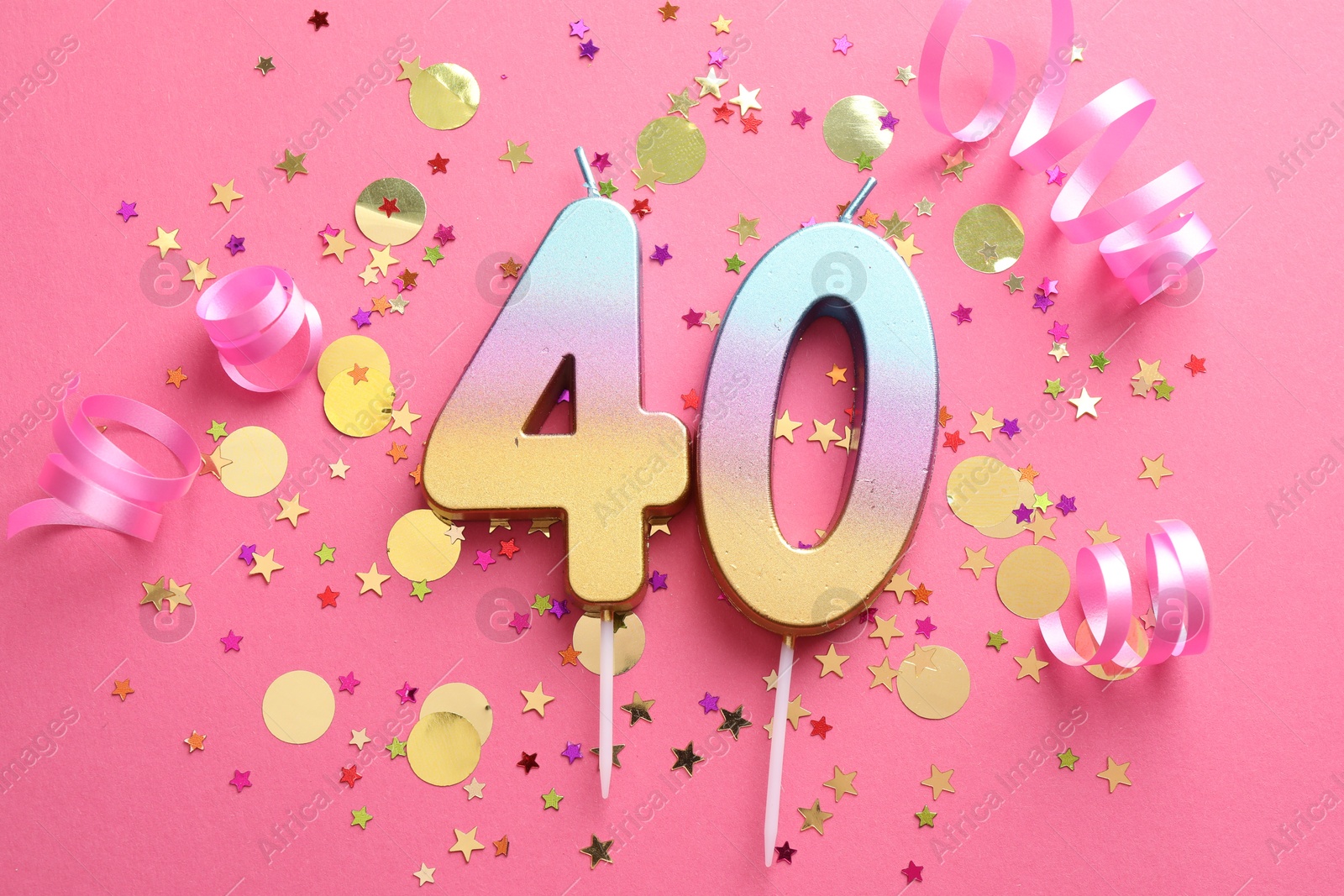 Photo of 40th birthday. Number shaped candles and confetti on pink background, flat lay