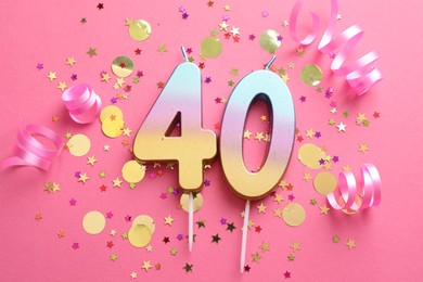 Photo of 40th birthday. Number shaped candles and confetti on pink background, flat lay