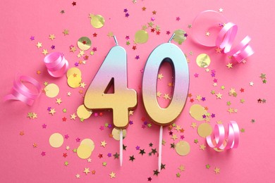 Photo of 40th birthday. Number shaped candles and confetti on pink background, flat lay