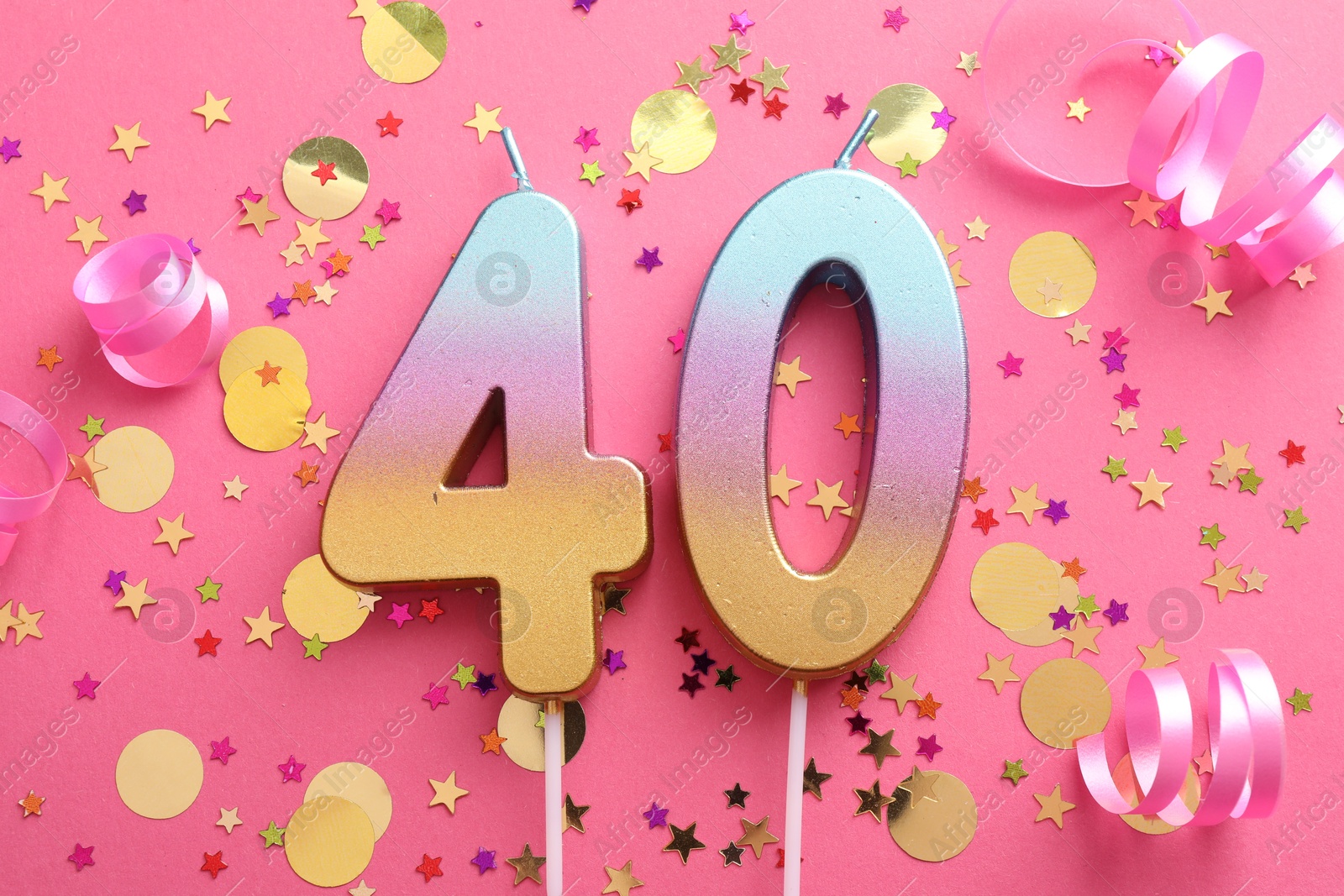 Photo of 40th birthday. Number shaped candles and confetti on pink background, flat lay