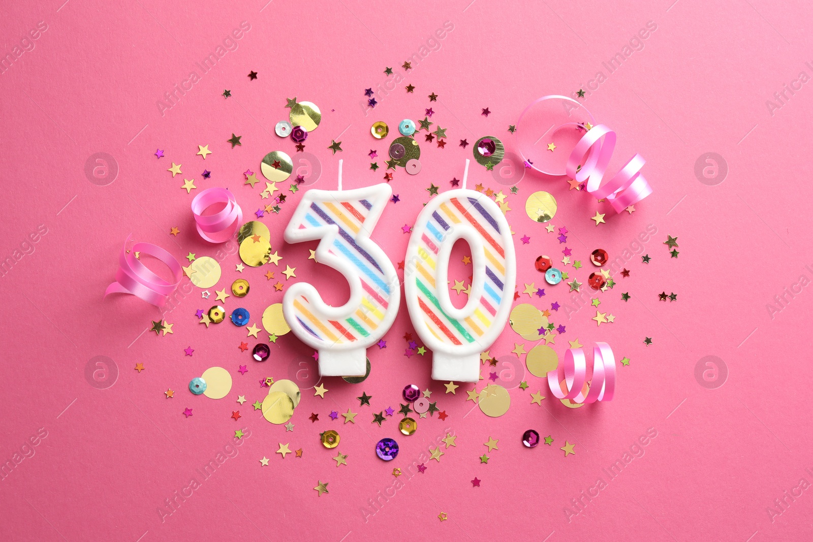 Photo of 30th birthday. Number shaped candles and confetti on pink background, flat lay