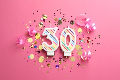 Photo of 30th birthday. Number shaped candles and confetti on pink background, flat lay