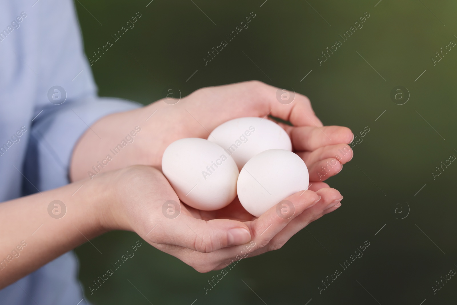 Photo of Woman with raw eggs on blurred background, closeup